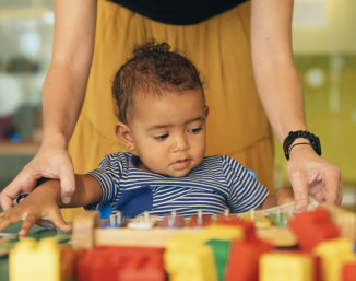 Woman assisting baby with toys